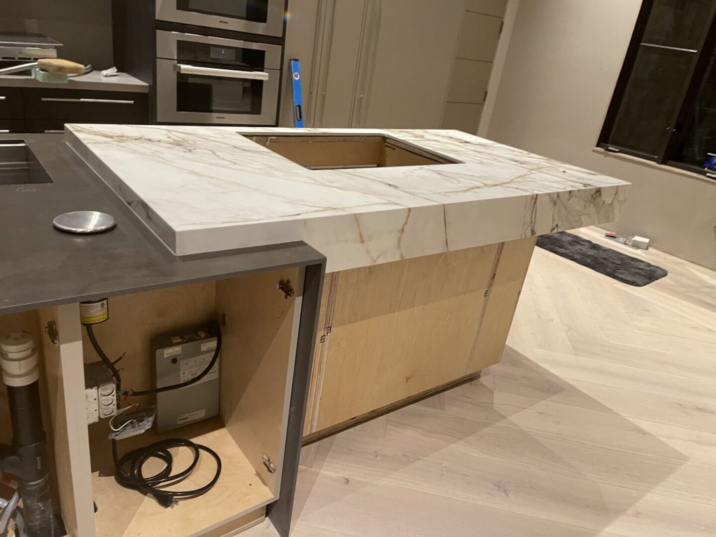 A kitchen island with unfinished marble countertop and wooden base.