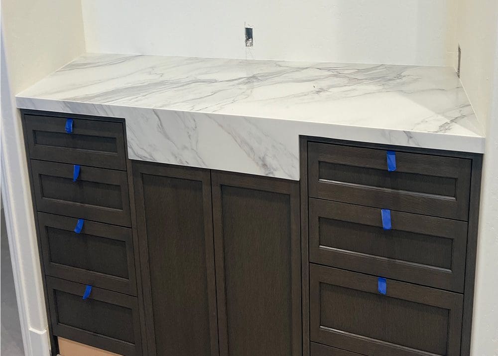 Modern kitchen cabinets with a marble countertop and blue handle accents.