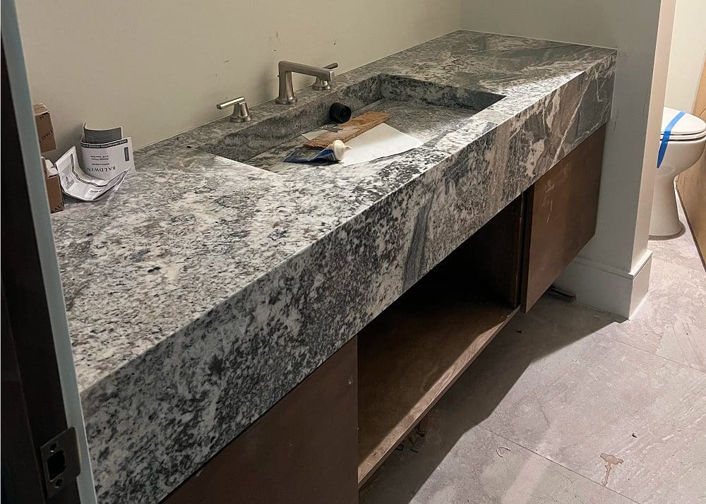 Granite countertop with a sink installed in a kitchen or bathroom under construction.