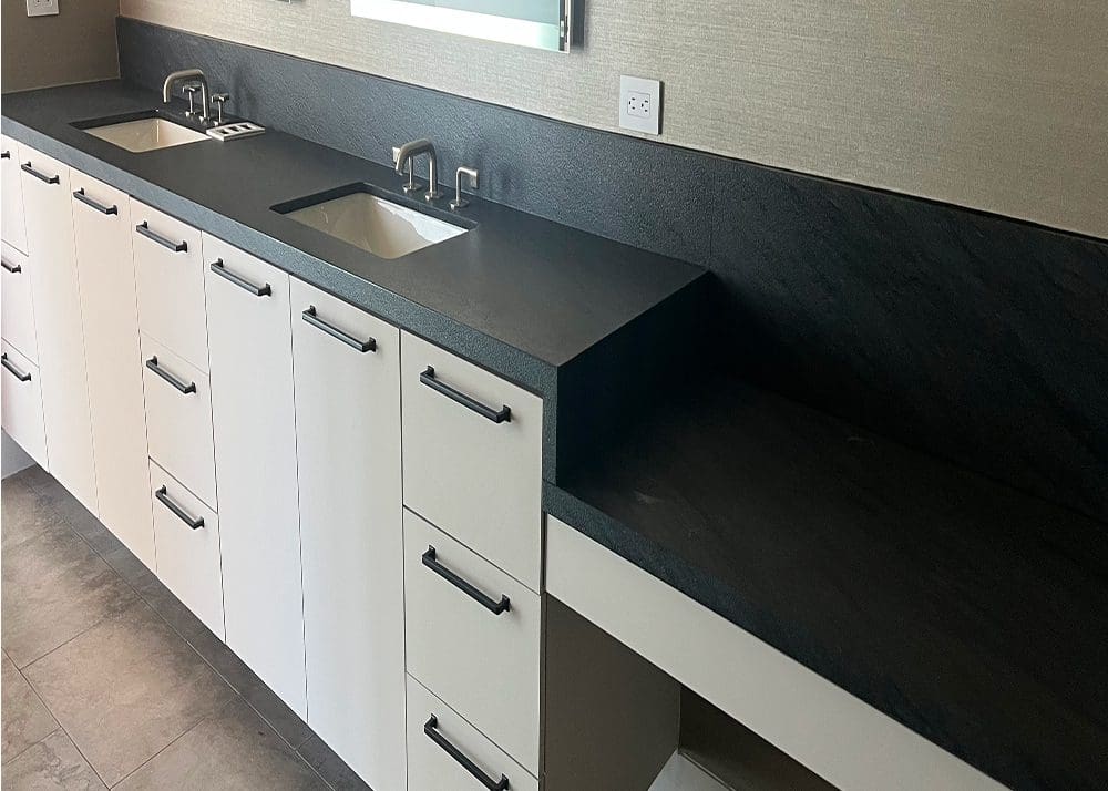 Modern kitchen sink with black countertop and white cabinets.