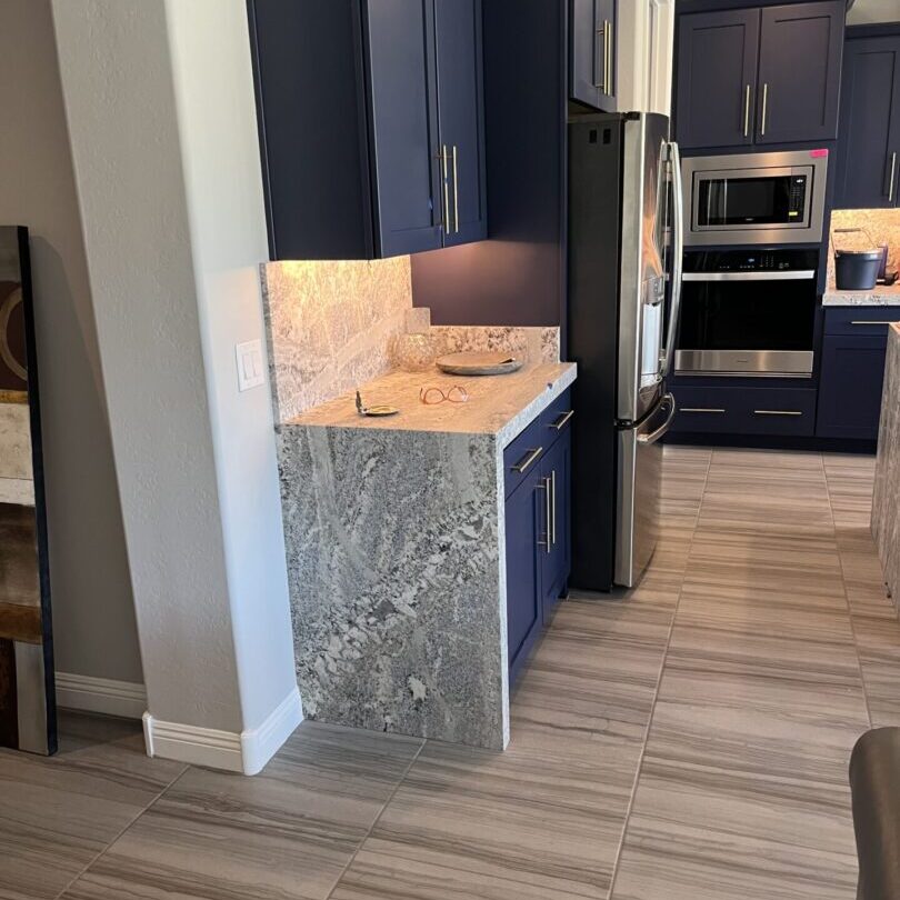 Marble countertop with blue cabinetry and modern appliances in a kitchen.
