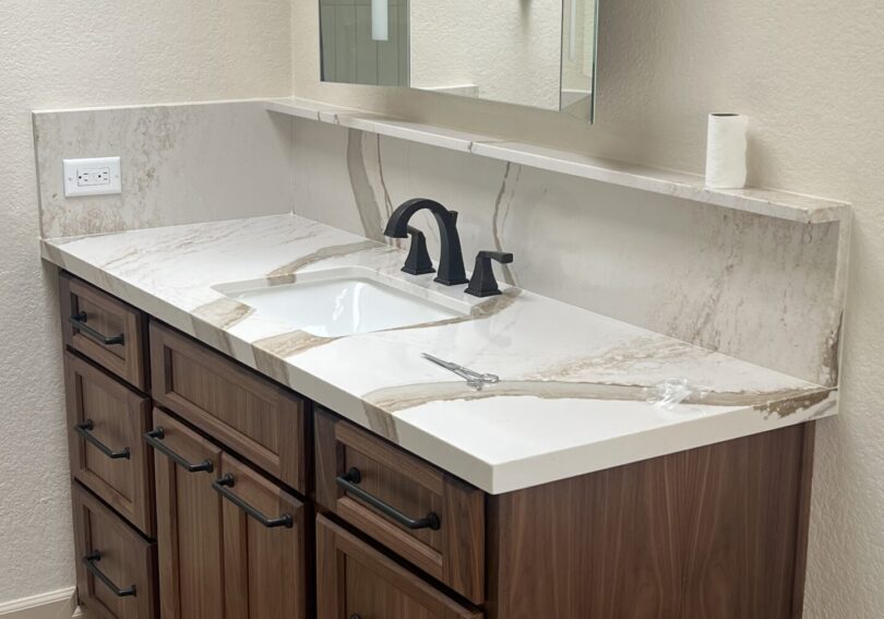 Elegant bathroom vanity with white marble countertop and dark wood cabinets.