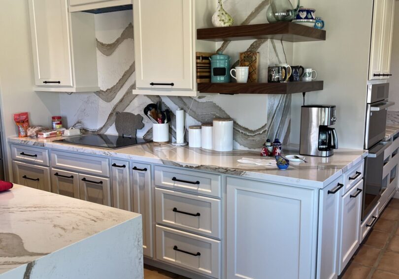 Modern kitchen with white cabinetry and marble countertops.